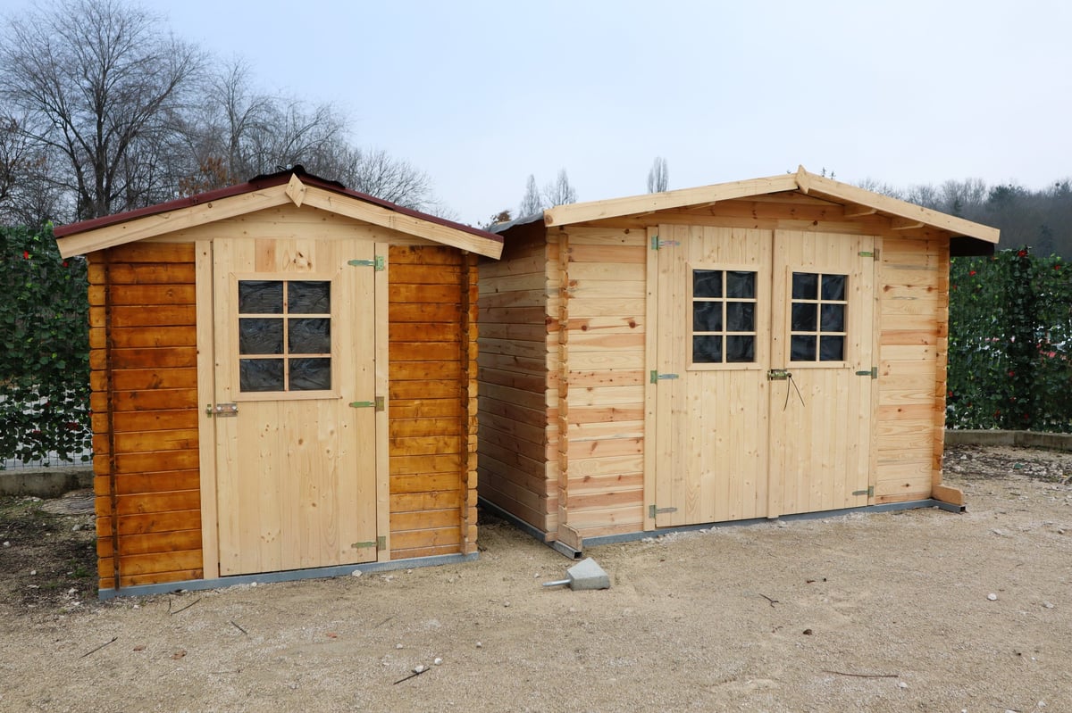 There are two wooden storage sheds that are perfect for storing gardening tools and providing outdoor storage solutions